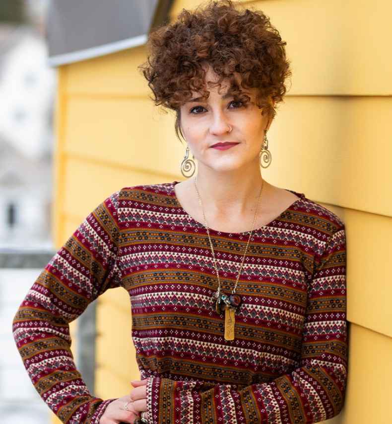 Participant Julia - person in red sweater standing in front of yellow building