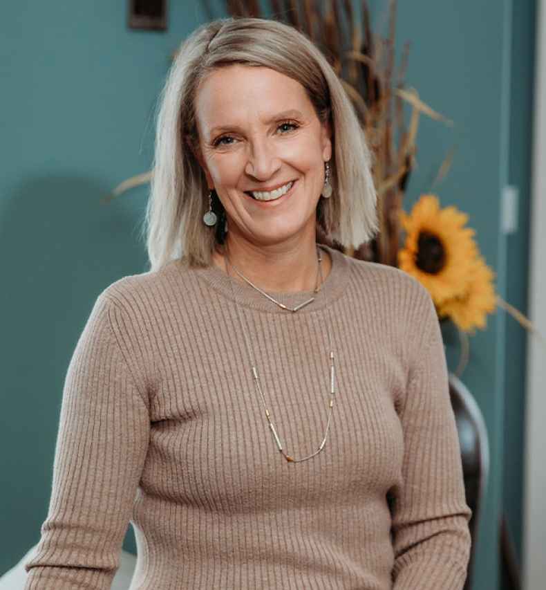 Participant Kelli - person in brown sweater in front of teal wall