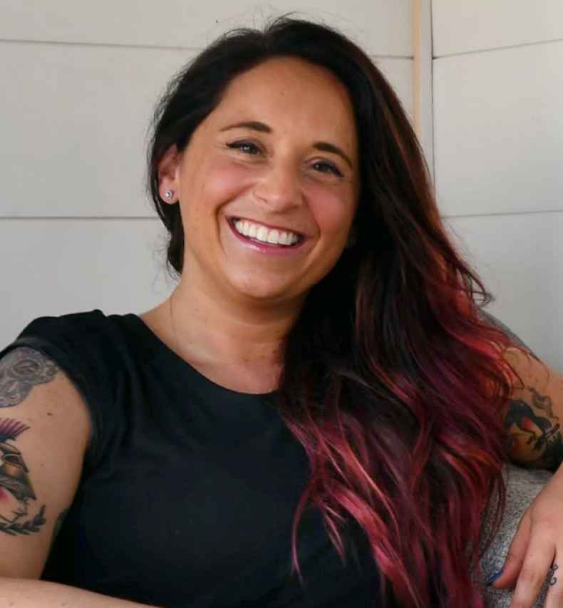 Participant Leslie - person with long dark hair smiling in a cushioned seat