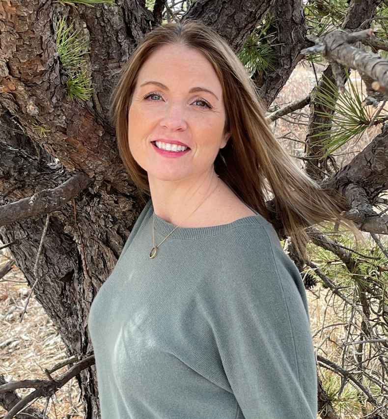 Participant Lindsay - person in sweater smiling in front of a tree