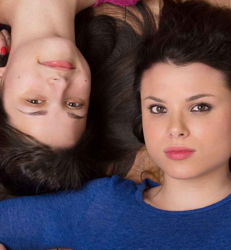 Participant Abby is lying on the floor holding hands with her sister Mary