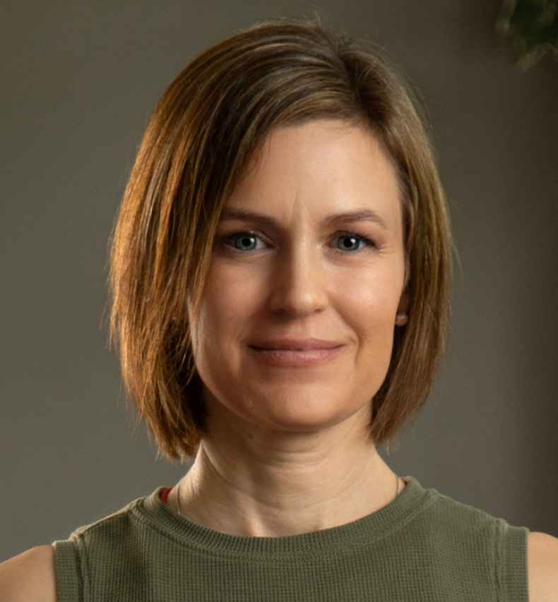 Participant Stephanie - person with short brown hair wearing a green tank top smiling in front of a grey wall