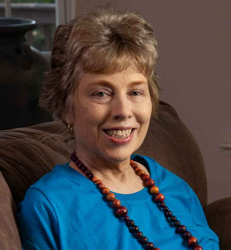 Participant Meredith - person with short blond hair wearing a teal shirt and a long necklace
