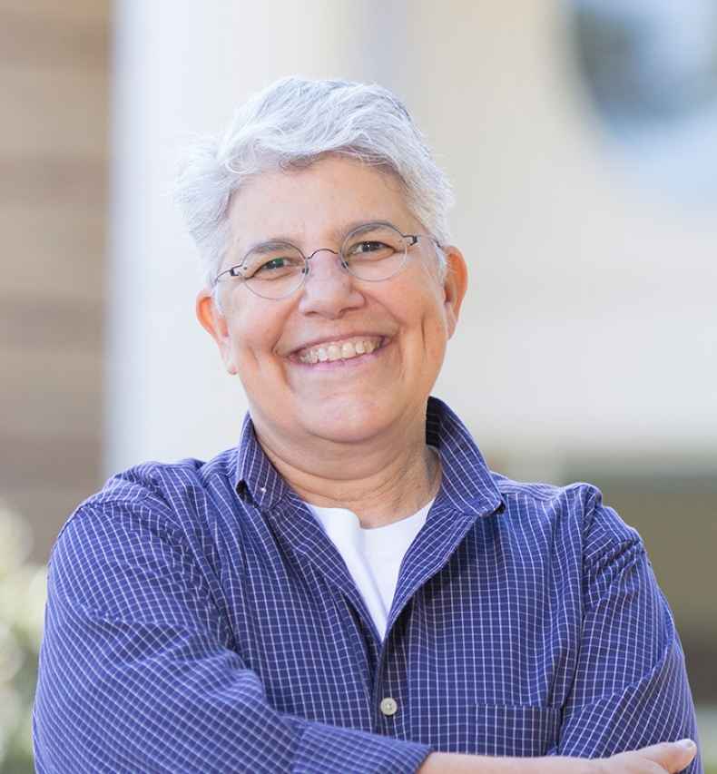 Participant Olga - person with short white hair wearing a blue shirt and smiling outside