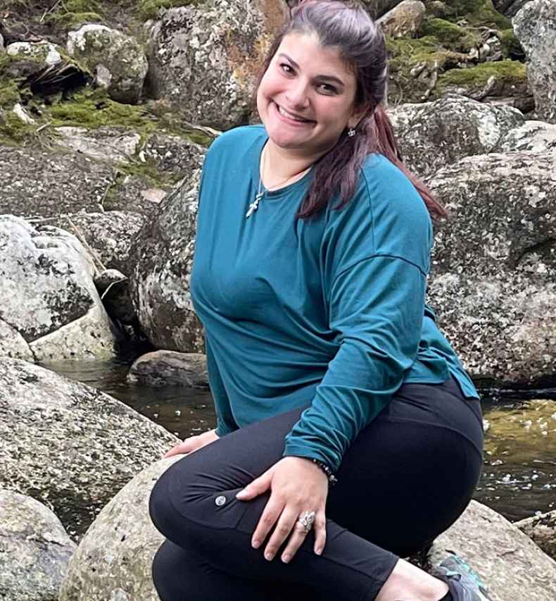 Participant Amanda sitting on a large rock in a stream