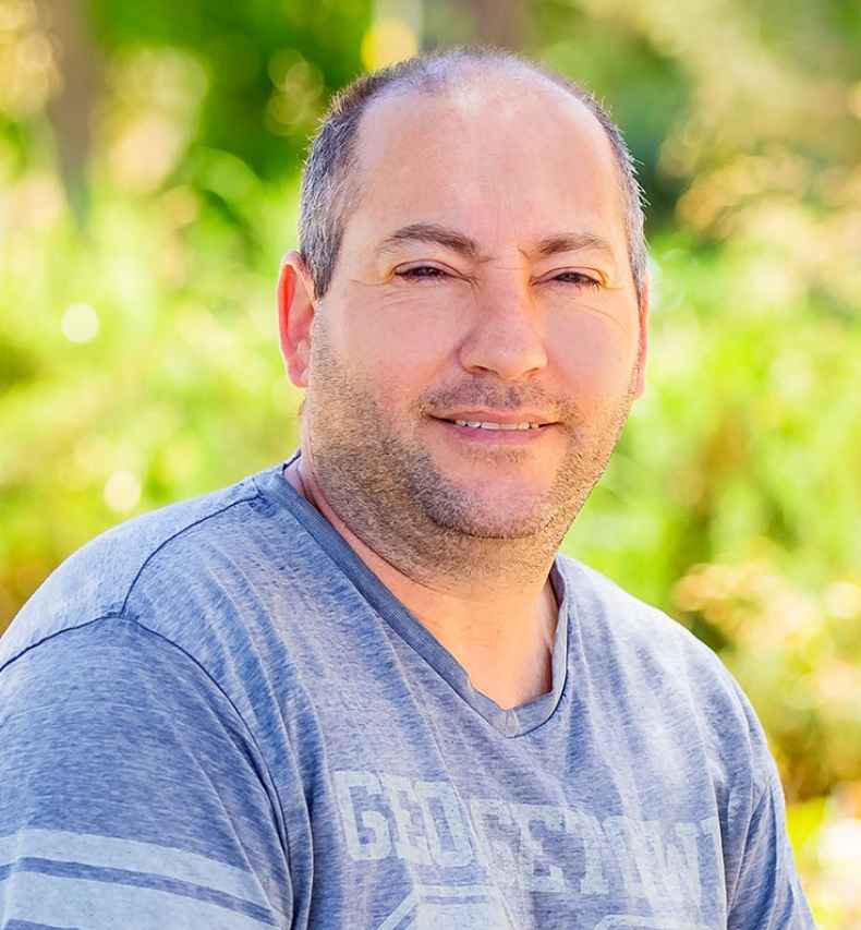 Deconstructing Stigma participant Eitan - person sits outside green plants in the background