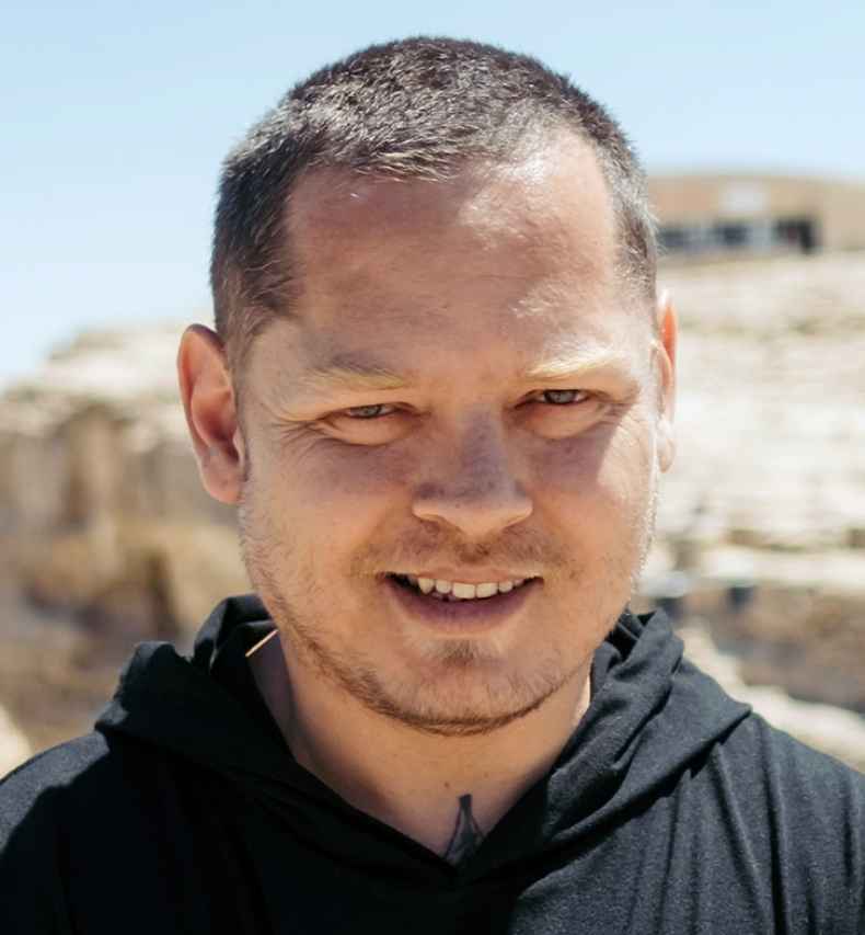 Deconstructing Stigma participant Lavih - Person stands outside in desert with boulder behind