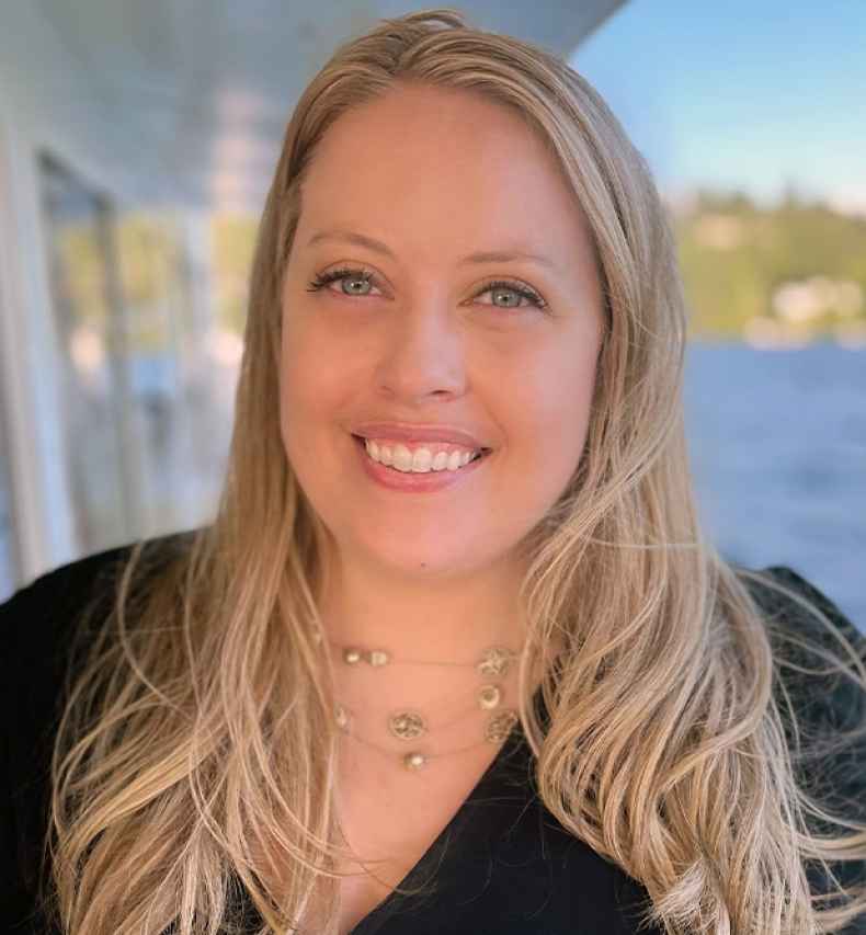 Participant Melissa - person with long blond hair smiling in front of a body of water