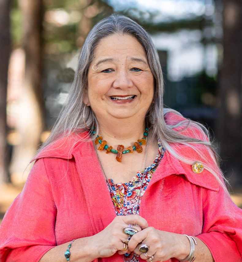 Participant Pata - person with long grey hair smiling outside