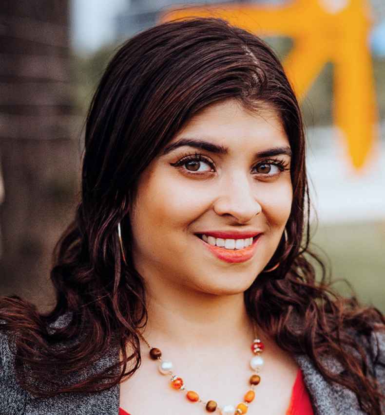 Participant Mrinal - person with wavy brown hair smiling outside