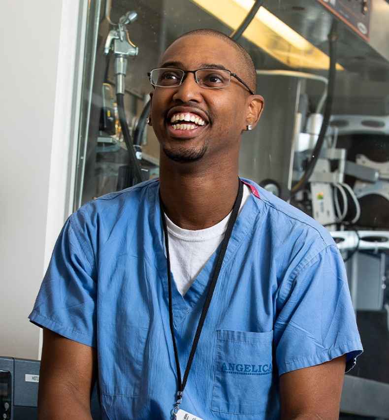 Participant Charles - person with very short hair and glasses wearing blue scrubs and laughing
