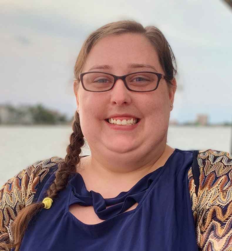 Participant Elizabeth - person with long dark hair and glasses smiling outside