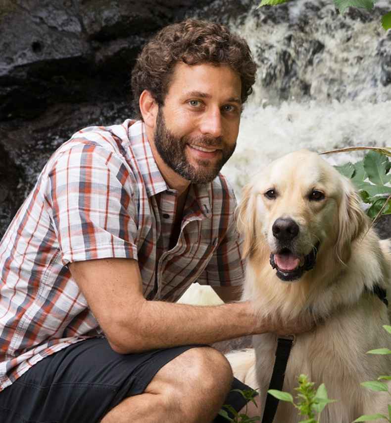 Participant Jeff - person with short curly brown hair smiling with a golden retriever outside