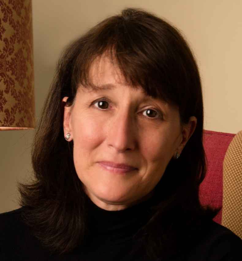 Participant Amy - person with dark brown hair smiling by a lamp
