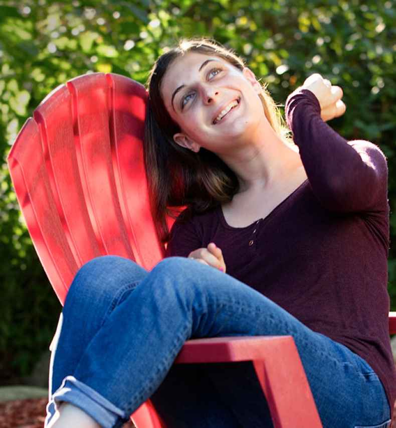Deconstructing Stigma participant Jessica - person sits and laughs on red outdoor chair