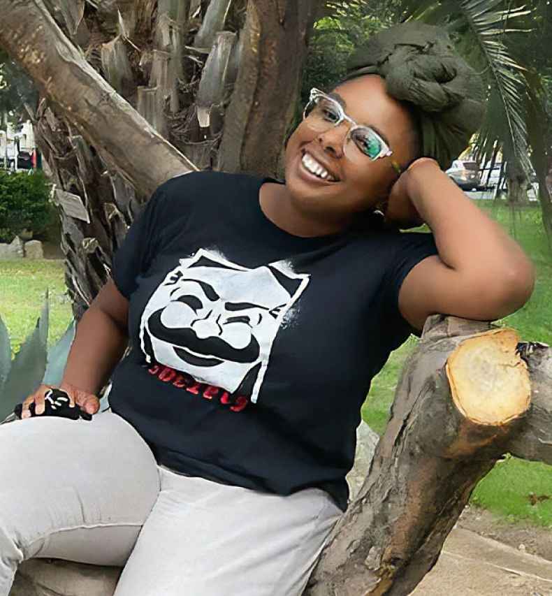 Participant Chezia sitting outside wearing a black t-shirt smiling