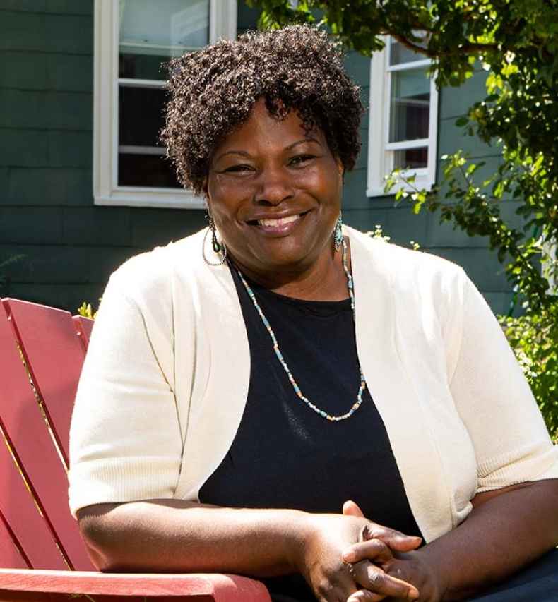 Participant Cynthia - person with dark curly hair sitting in a red chair and smiling