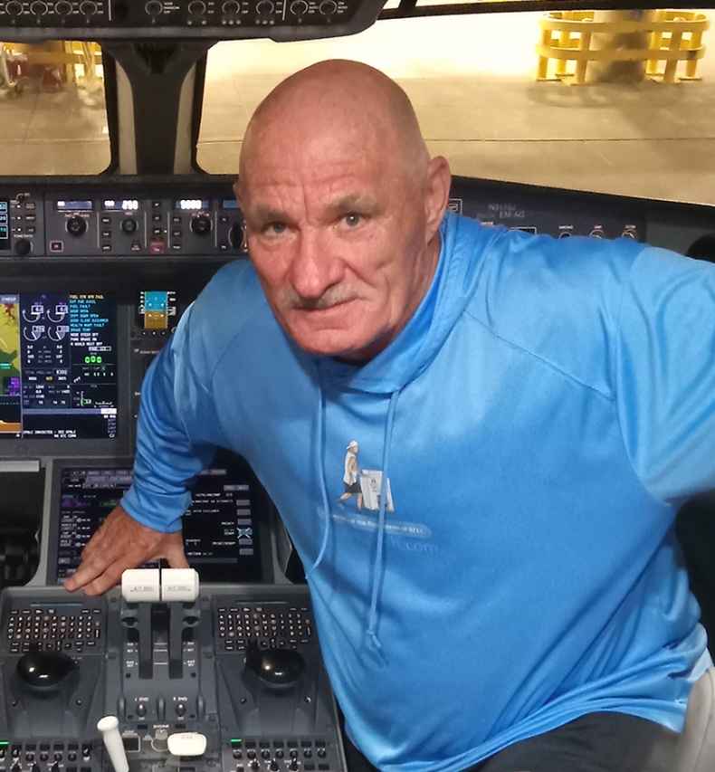 Deconstructing Stigma participant Paul - person in blue hoodie perches in airplane cockpit