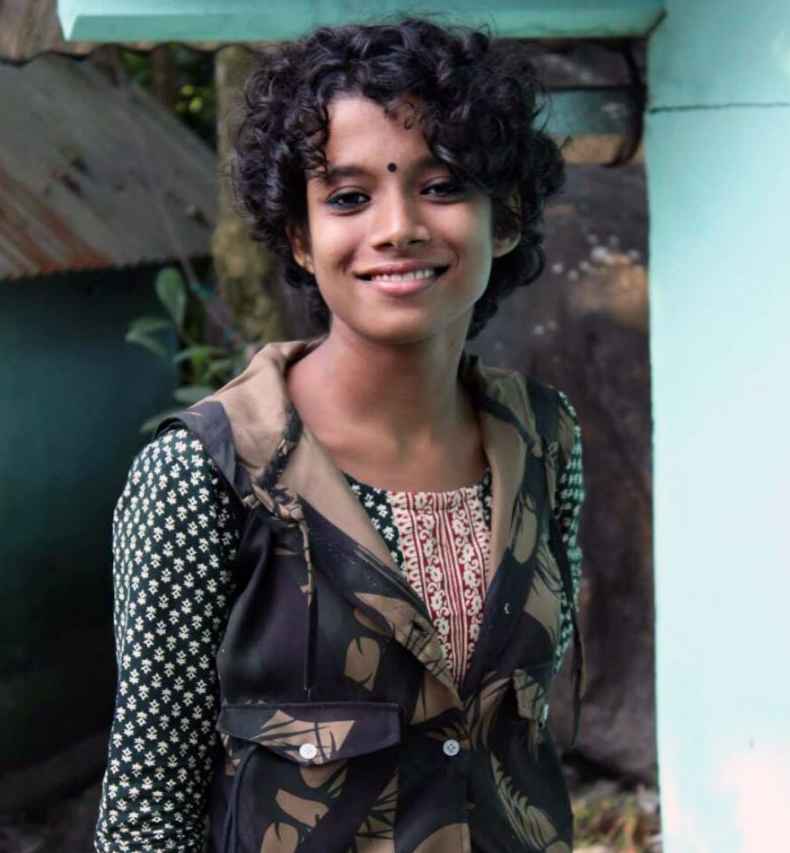 Deconstructing Stigma participant Sampurna - person with curly dark hair poses for camera