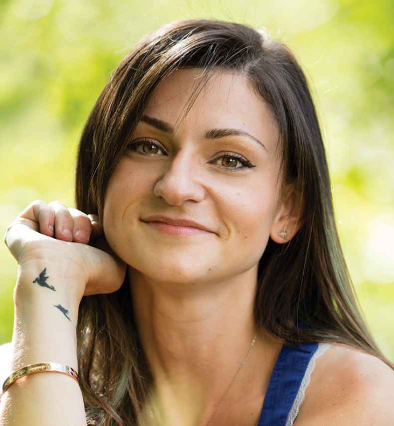 Deconstructing Stigma participant Jessika - woman sits outside, shows wrist tattoo