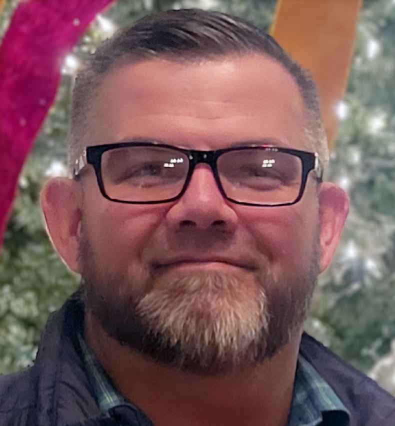 Deconstructing Stigma participant Tom - person with glasses in front of indoor decorated tree