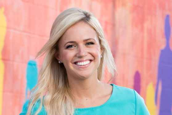 Participant Meg - person with long blond hair smiling in front of a colorful painted wall