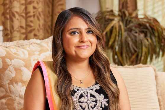Participant Dimple - person with long wavy hair smiling on a couch