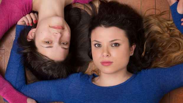 Participant Abby is lying on the floor holding hands with her sister Mary