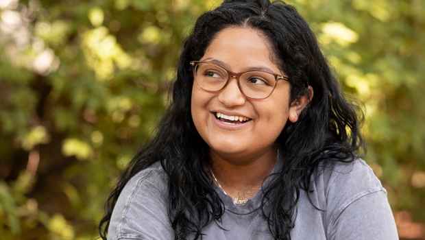 Participant Marina - person with dark hair and glasses wearing a grey t-shirt and laughing