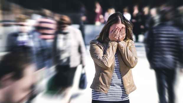 Person stands in crowd with hands over eyes