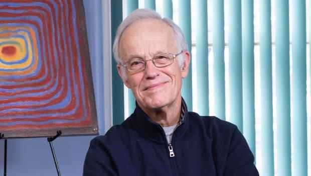 Participant Robert - person with short white hair and glasses smiling with a piece of art