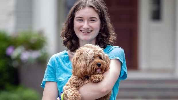 Participant Caroline - person with short brown hair holding a dog and smiling outside