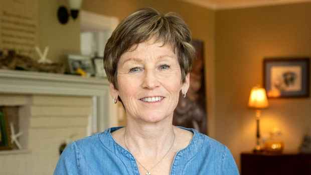 Participant Ann - person with short blond hair smiling in a room with a lamp