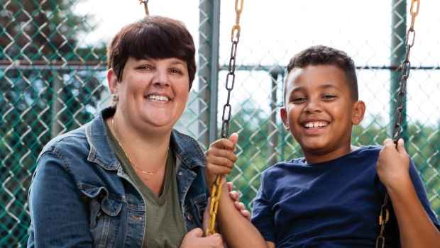Participant Jennifer - person with short dark hair smiling with a child on a swing set