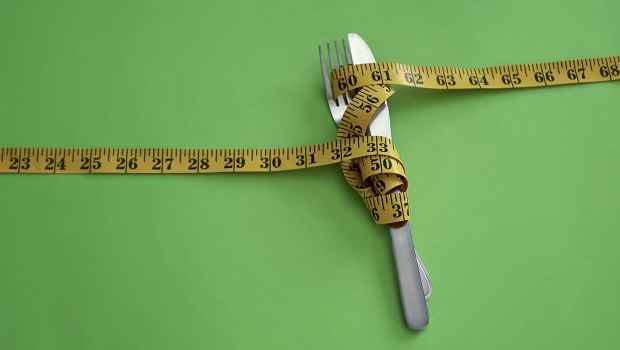 Measuring tape, knife, and fork on green background