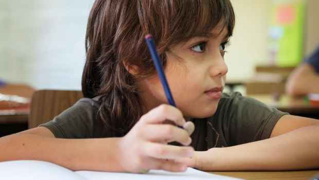 Child holds pencil in classroom