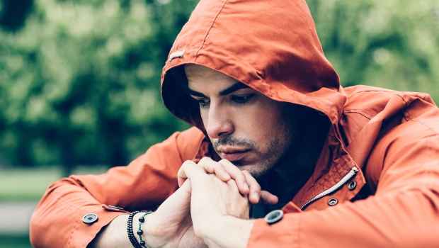 Person in orange hoodie sits outside