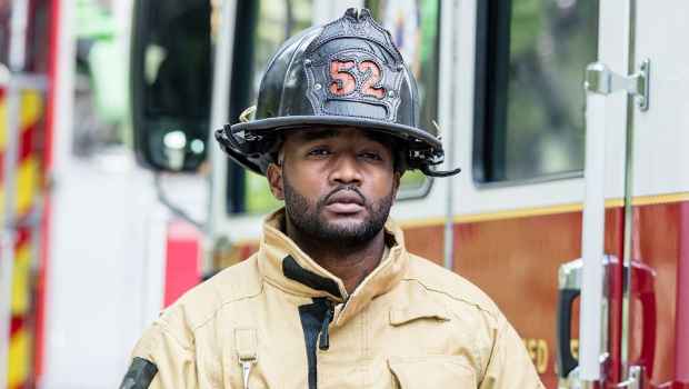 Stock image of firefighter in full gear standing by fire truck