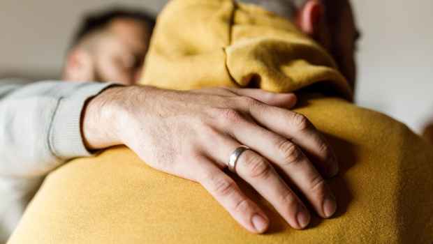 Hand on shoulder of individual in golden yellow hoodie