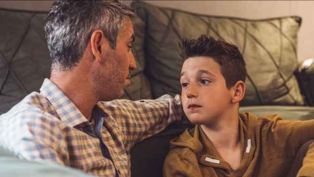 Man and boy sitting on the floor in front of a couch