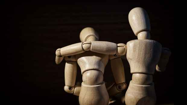 Artist mannequins posed on an embrace of support, black background