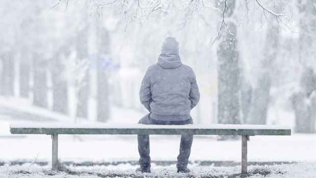 Figure sits on bench on snowy day