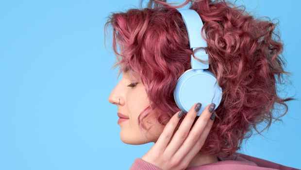 Young woman with pink hair wearing headphones