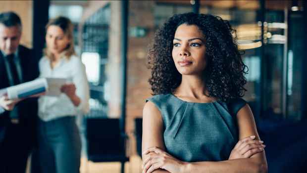 Woman in office stands away from a group of colleagues