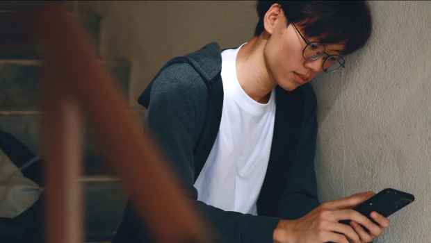 Teen sitting on stairs looking at his phone