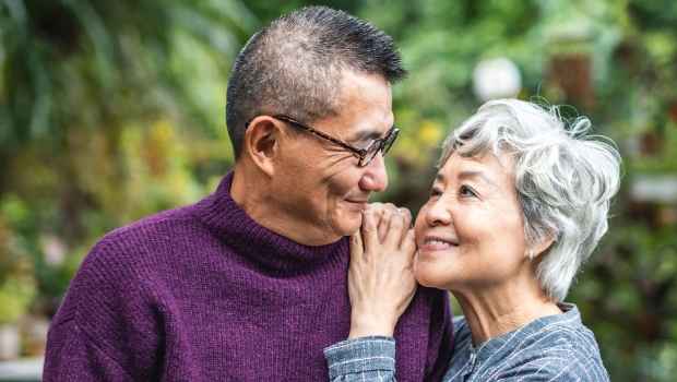 Two older adults looking lovingly at one another outside among greenery