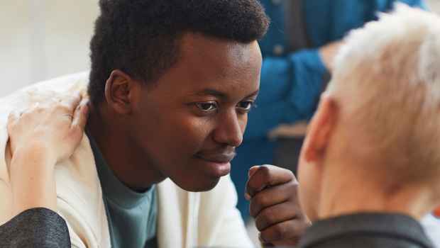 Young man is comforted by person with hand on shoulder