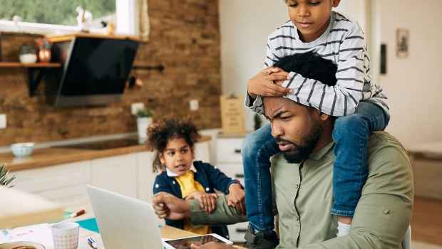 Boy on dad’s shoulders with sister watching