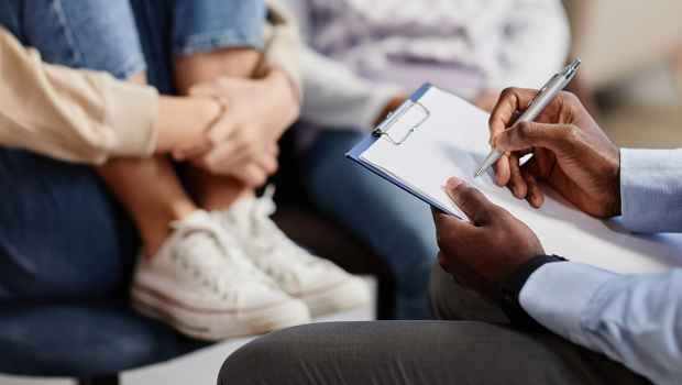 therapist writing on clipboard with child in background
