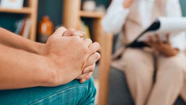 Person sitting in therapy session with hands clasped
